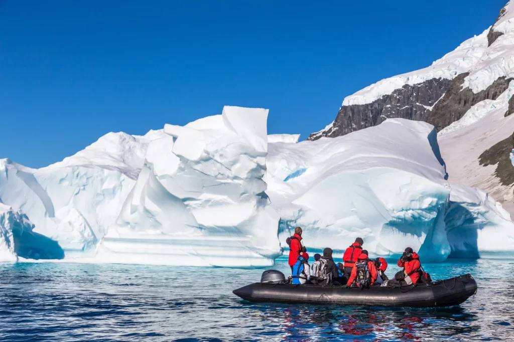 Boat full of tourists explore huge icebergs drifting in the bay