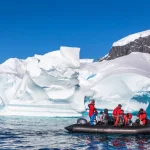 Boat full of tourists explore huge icebergs drifting in the bay