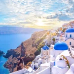 Beautiful Oia town on Santorini island, Greece. Traditional white architecture  and greek orthodox churches with blue domes over the Caldera, Aegean sea. Scenic travel background.